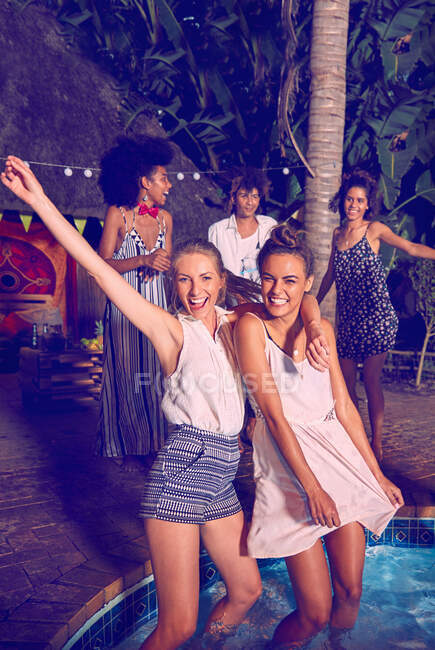 Retrato exuberante de las jóvenes amigas de fiesta, baile y vadeo en la fiesta de la piscina - foto de stock