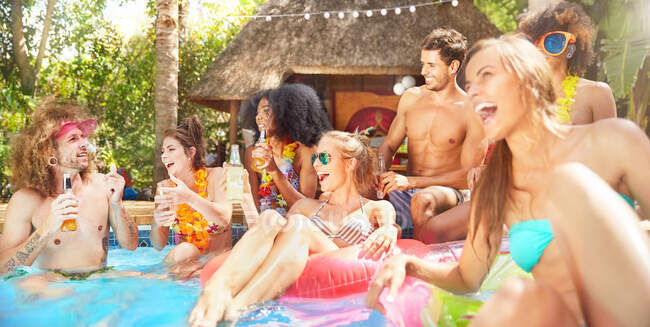 Молоді друзі сміються, зависають і п'ють в сонячному літньому басейні — стокове фото