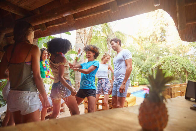 Young friends dancing and hanging out at tropical summer poolside — Stock Photo