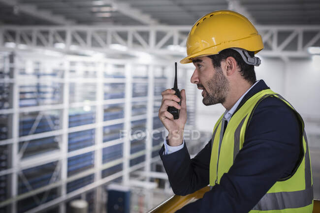Male supervisor talking, using walkie-talkie on platform in factory — Stock Photo