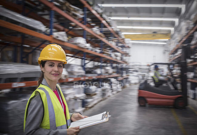 Portrait confident, smiling female worker with clipboard in warehouse — Stock Photo