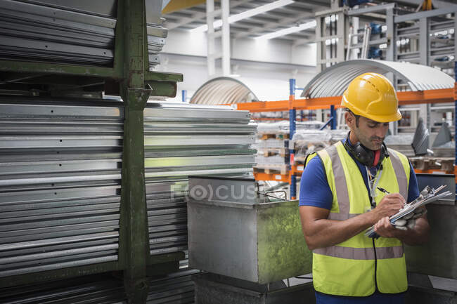 Travailleur masculin avec presse-papiers travaillant dans une usine d'acier — Photo de stock
