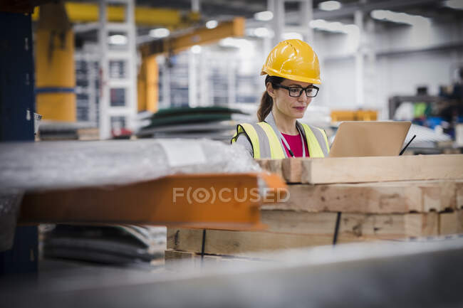 Female worker using laptop in factory — Stock Photo