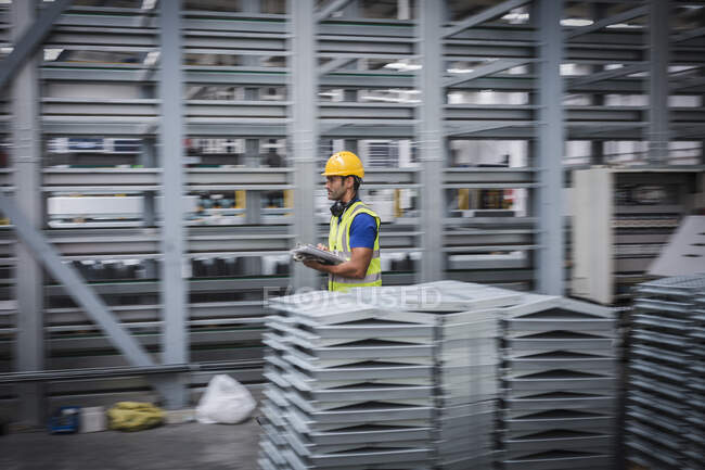 Männlicher Arbeiter mit Klemmbrett läuft in Stahlfabrik — Stockfoto