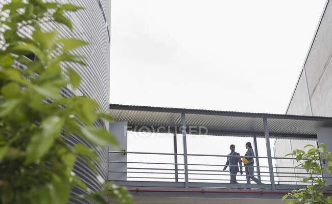 Supervisors walking on elevated walkway between factory buildings — Stock Photo
