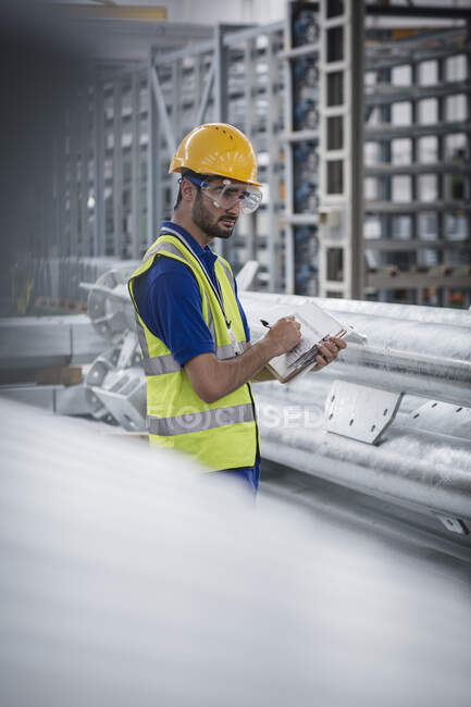 Male worker with clipboard working in steel factory — Stock Photo