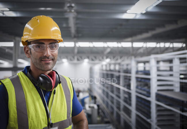 Retrato de trabajador masculino con protectores de oídos en fábrica — Stock Photo