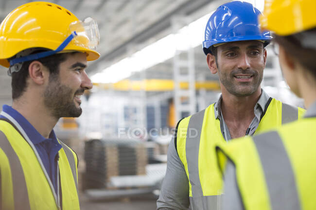 Lavoratori sorridenti che parlano in fabbrica — Foto stock