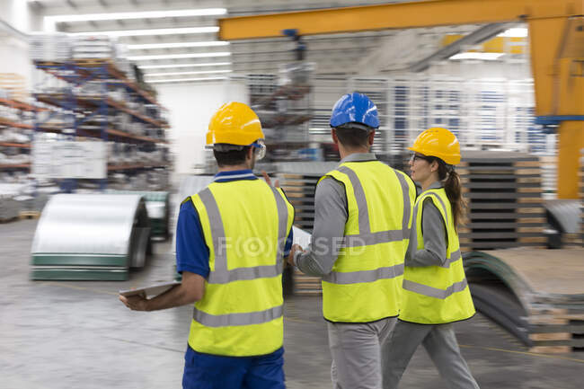 Trabajadores caminando y hablando en fábrica - foto de stock