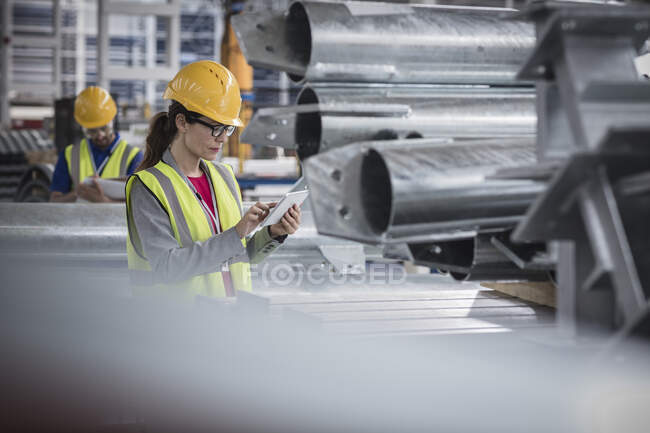 Жінка-контролер, що використовує цифровий планшет на металургійному заводі — стокове фото