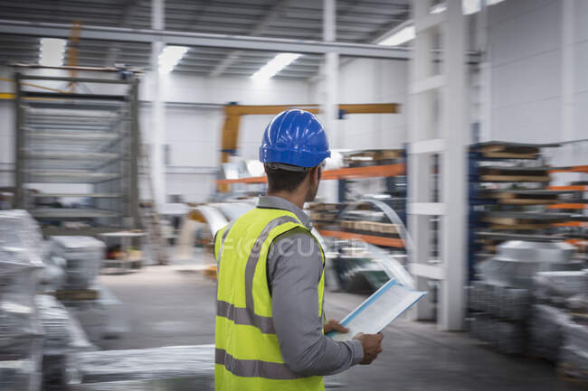 Male supervisor with paperwork walking in warehouse — Stock Photo