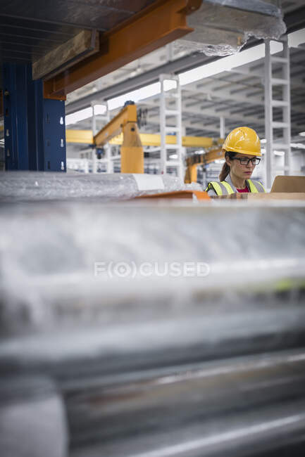 Сфокусированная женщина-работница с ноутбуком на сталелитейном заводе — стоковое фото