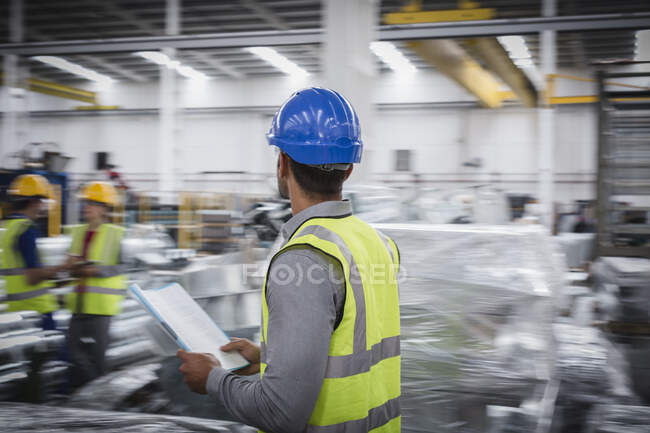 Чоловічий керівник з паперовими роботами, що йдуть на металургійному заводі — стокове фото