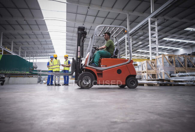 Männlicher Arbeiter fährt Gabelstapler in Fabrik — Stockfoto