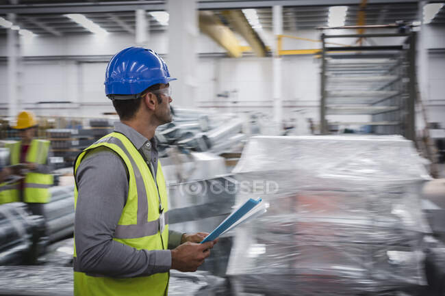 Male supervisor with paperwork walking in factory — Stock Photo