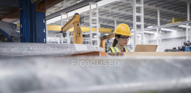 Female supervisor using laptop in factory — Stock Photo