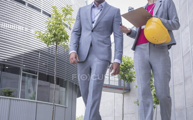 Supervisores com chapéu duro e prancheta andando e conversando — Fotografia de Stock