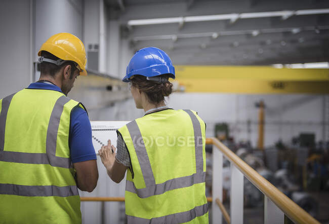 Supervisores discutindo papelada na plataforma na fábrica — Fotografia de Stock