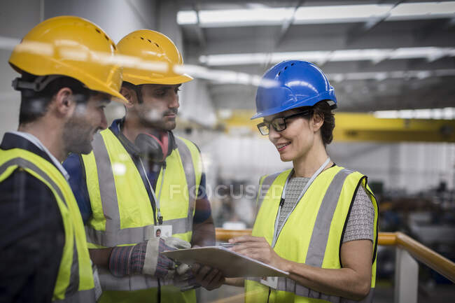 Supervisores com área de transferência falando na plataforma na fábrica — Fotografia de Stock