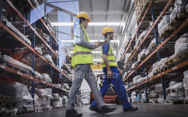 Trabajadores con portapapeles caminando en almacén - foto de stock