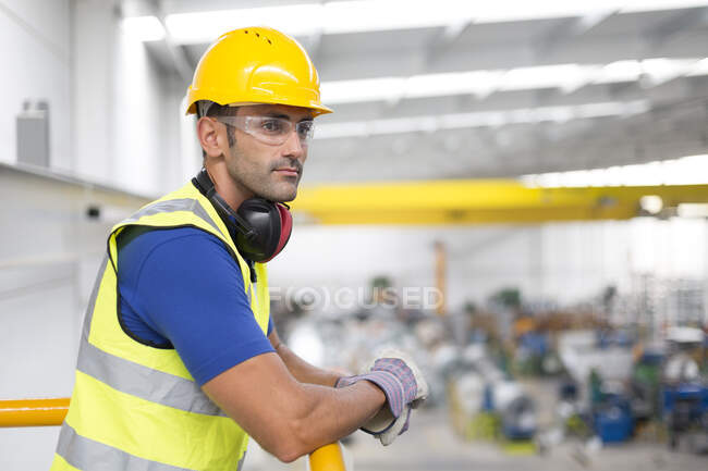 Serious male supervisors leaning on platform railing in factory — Stock Photo
