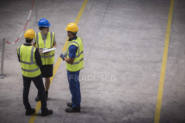 Supervisor e trabalhadores com área de transferência falando na fábrica — Fotografia de Stock