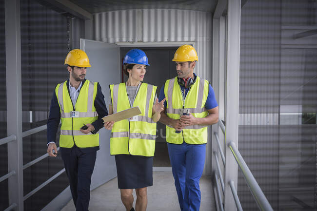 Supervisors with clipboard walking and talking on factory walkway — Stock Photo