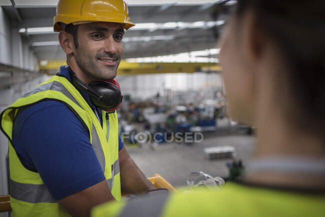 Усміхнений чоловік-наглядач розмовляє з колегою на платформі на заводі — стокове фото