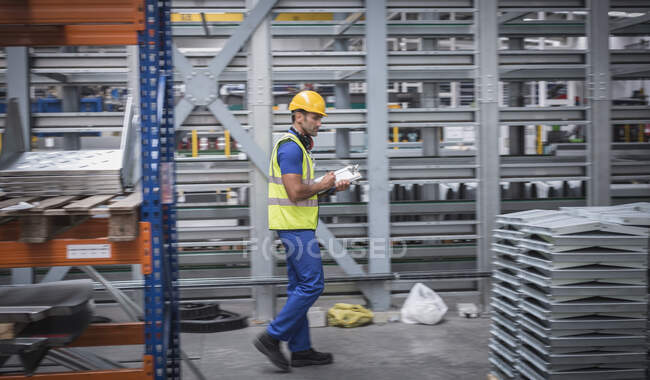 Supervisor masculino com prancheta verificando inventário em armazém de aço — Fotografia de Stock