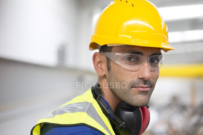 Retrato trabalhador masculino grave em óculos de proteção e chapéu duro na fábrica — Fotografia de Stock