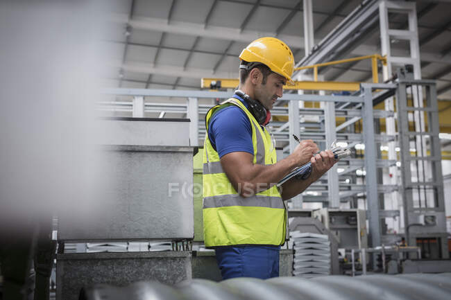 Supervisor masculino escrevendo na área de transferência na fábrica — Fotografia de Stock