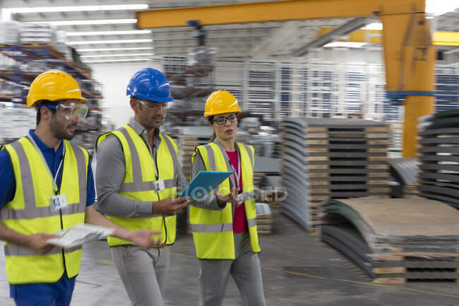 Vorgesetzter und Arbeiter mit Klemmbrett und digitalem Tablet gehen in Fabrik — Stockfoto