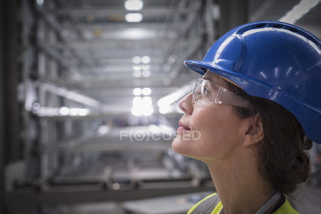 Profil nachdenkliche Arbeiterinnen, die in Fabrik nach oben schauen — Stockfoto