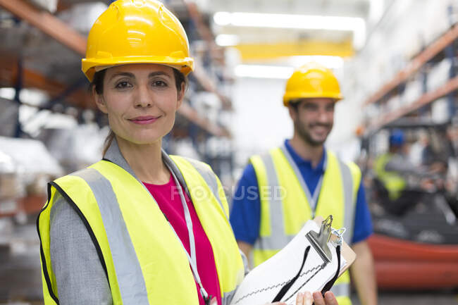 Portrait confident female supervisor with clipboard in warehouse — Stock Photo