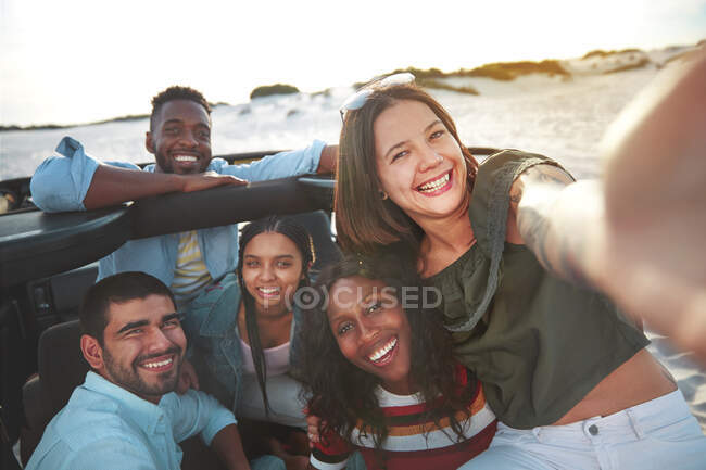 Portrait smiling young friends taking selfie at beach — Stock Photo