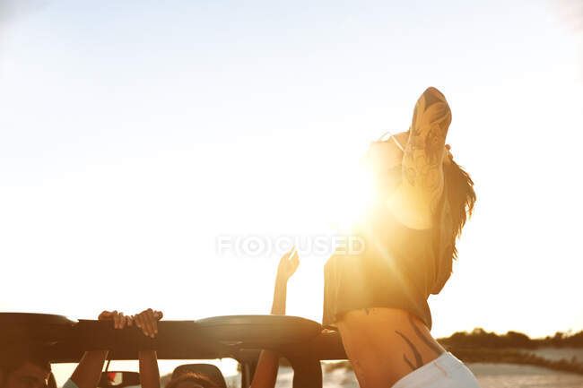Giovane donna esuberante con tatuaggi sulla spiaggia soleggiata — Foto stock