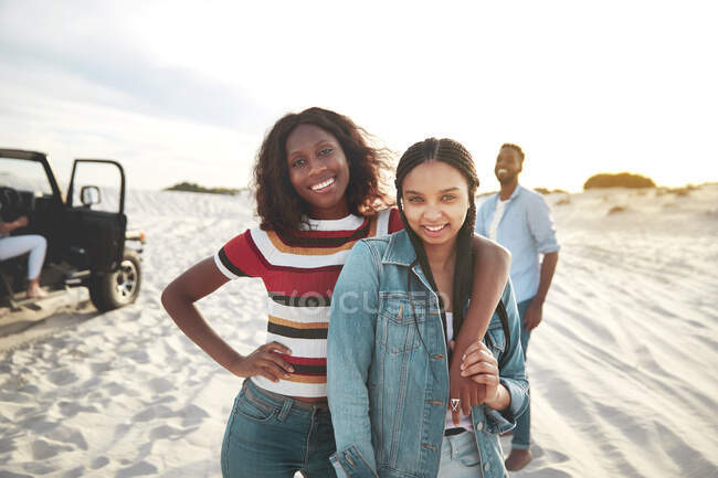 Retrato sonriente mujeres jóvenes abrazándose en la playa - foto de stock