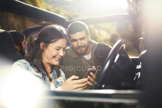 Junges Paar checkt GPS auf Smartphone und genießt Roadtrip im Jeep — Stockfoto