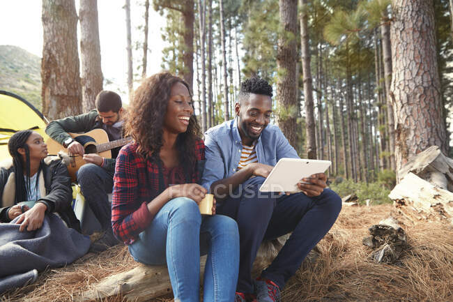 Sorrindo jovem casal usando tablet digital no parque de campismo na floresta — Fotografia de Stock