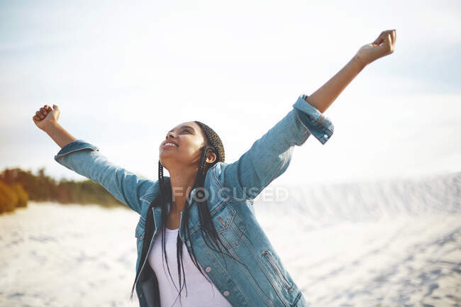 Exuberant young woman with arms outstretched on beach — Stock Photo