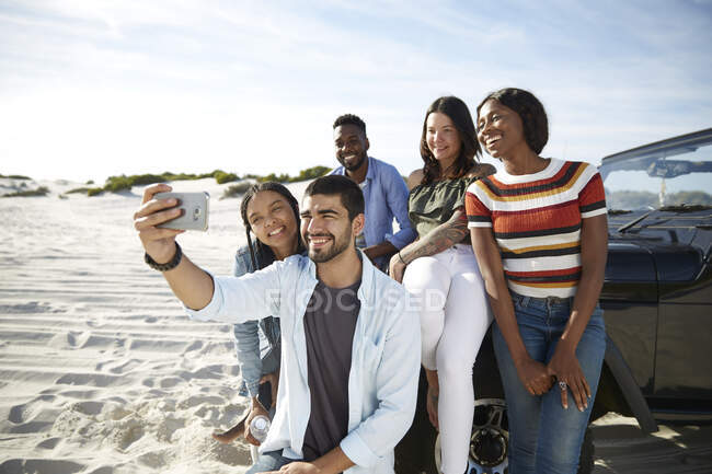 Young friends with camera phone taking selfie on beach — Stock Photo