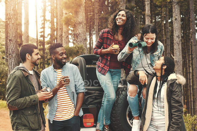 Young friends hanging out, drinking coffee at jeep in woods — Stock Photo