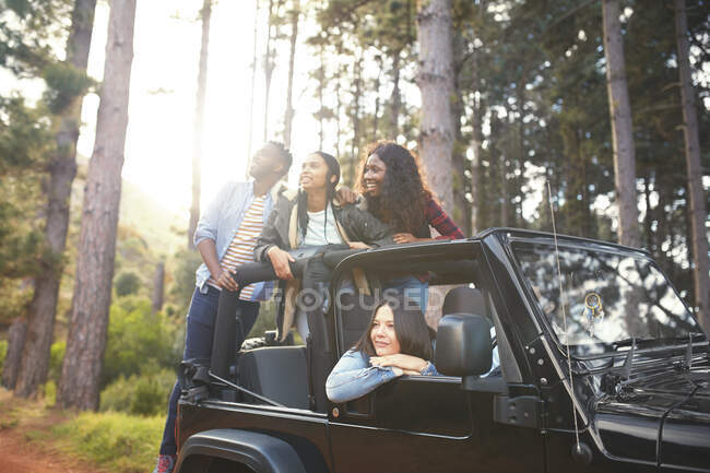 Young friends in jeep looking up at trees in woods, enjoying road trip — Stock Photo