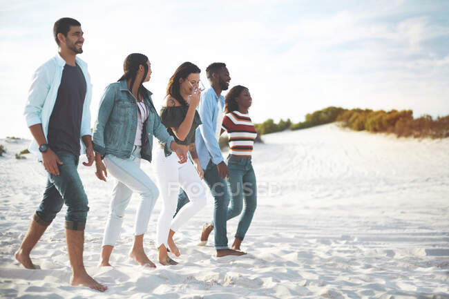 Jeunes amis marchant sur la plage ensoleillée — Photo de stock