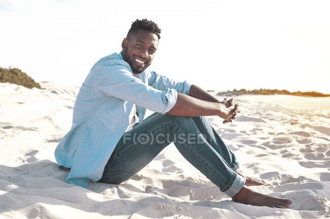 Портрет улыбающийся, уверенный молодой человек отдыхает на солнечном летнем пляже — стоковое фото