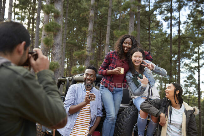 Junger Mann mit Digitalkamera fotografiert Freunde bei Jeep im Wald — Stockfoto