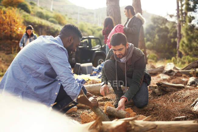 Young men friends building campfire at campsite — Stock Photo