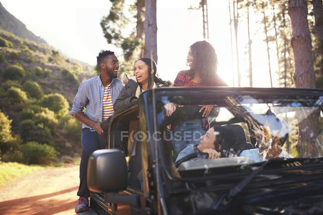 Young friends enjoying road trip in jeep in woods — Stock Photo