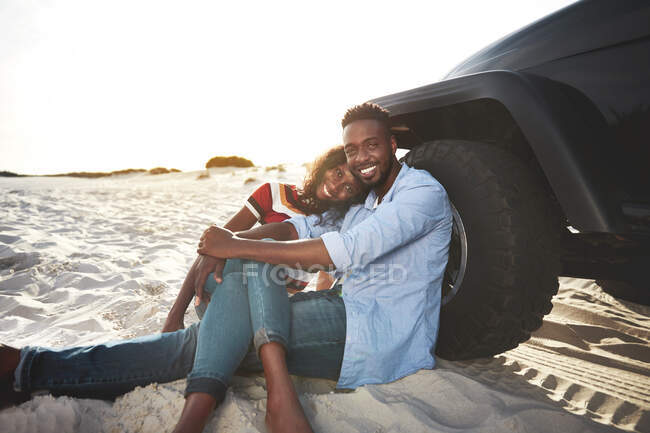 Portrait affectionate young couple relaxing at jeep on beach — Stock Photo