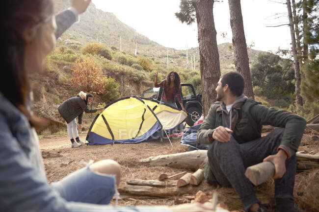 Junge Freunde bauen Lagerfeuer und schlagen Zelt auf Zeltplatz im Wald auf — Stockfoto